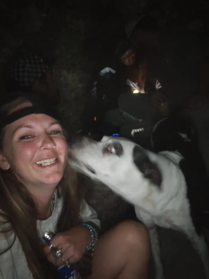 A guest smiling as a black-and-white dog leans in beside her.